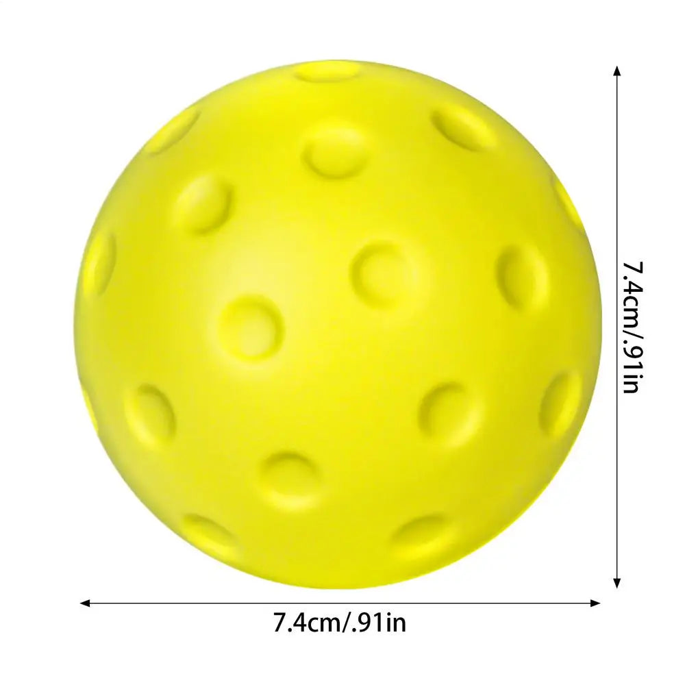 Balle de pickleball en mousse jaune vue de face sur fond blanc, avec ses cotes de 7,4 cm en hauteur et largeur