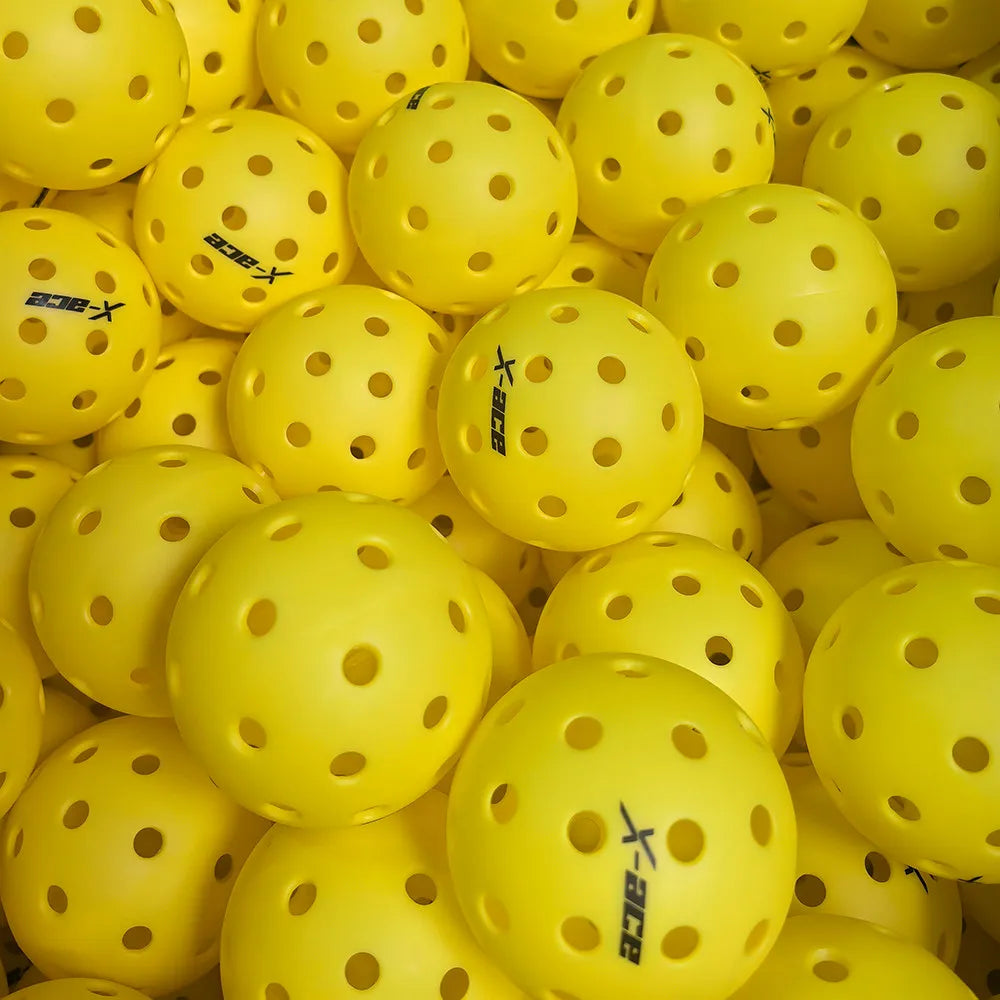 Balles de pickleball X-ace extérieur jaunes vues du dessus, des dizaines de balles perforées entassées