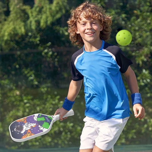 Raquette de pickleball enfant Joysent décor astronaute tenue par un garçon en maillot bleu qui court vers la balle