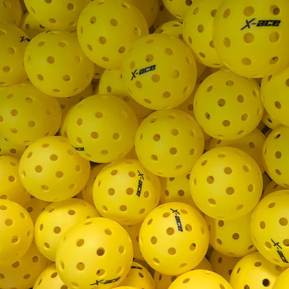 Balles de pickleball X-ace jaunes en grand nombre, logos noirs orientés dans tous les sens sur les balles à 40 trous