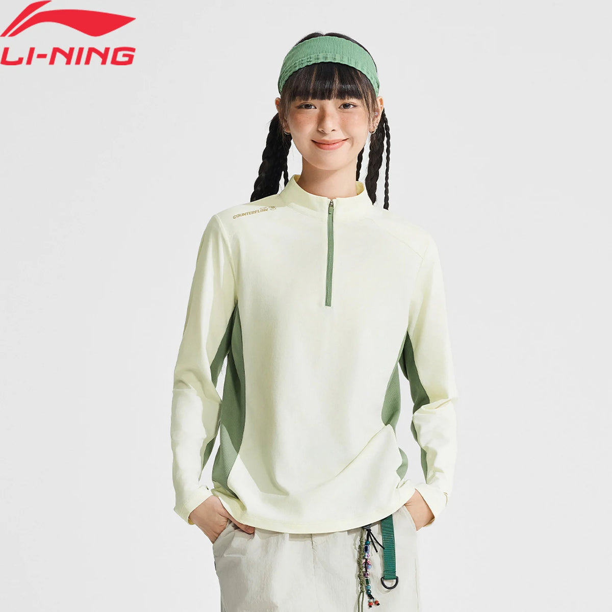 Haut manches longues femme Li-Ning écru et vert sauge porté, col montant demi-zip et empiècements latéraux verts